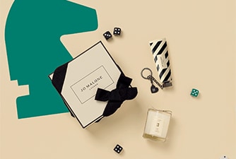 Launch image of advent calendar dartboard box shown open with examples of 5 product contents on checkerboard background.