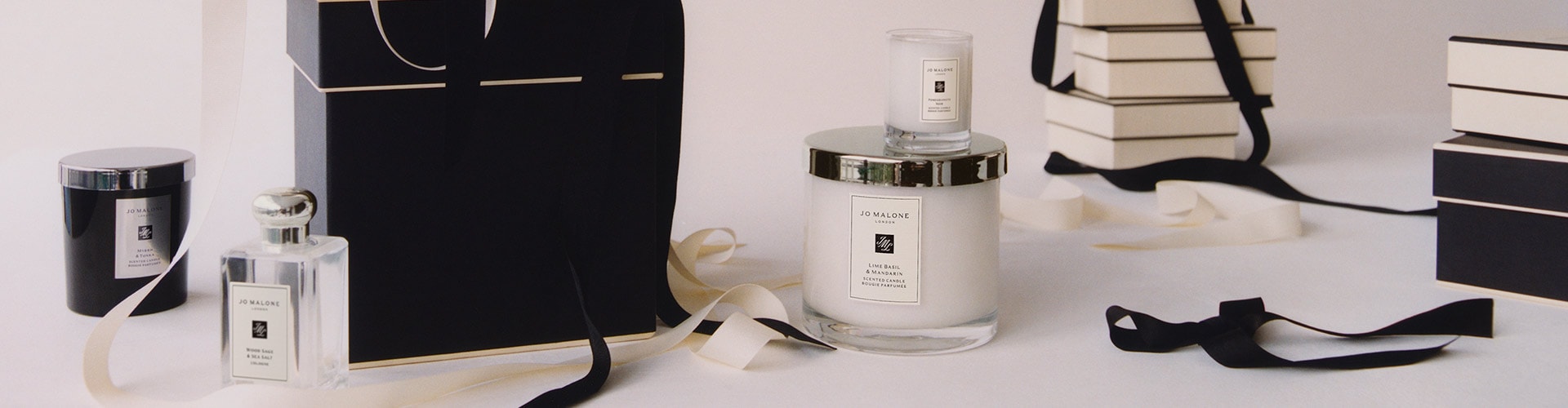 Jo Malone London Gift Boxes Stacked up on top of each other surrounded by flowers